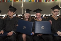 Students with diplomas in caps and gowns