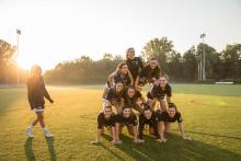 bentley students in human pyramid on lacrosse field