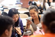 two students smile looking at their phones