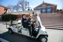 Two people in a golf cart on Bentley's campus