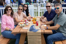 Smiling alumni gather at a picnic table