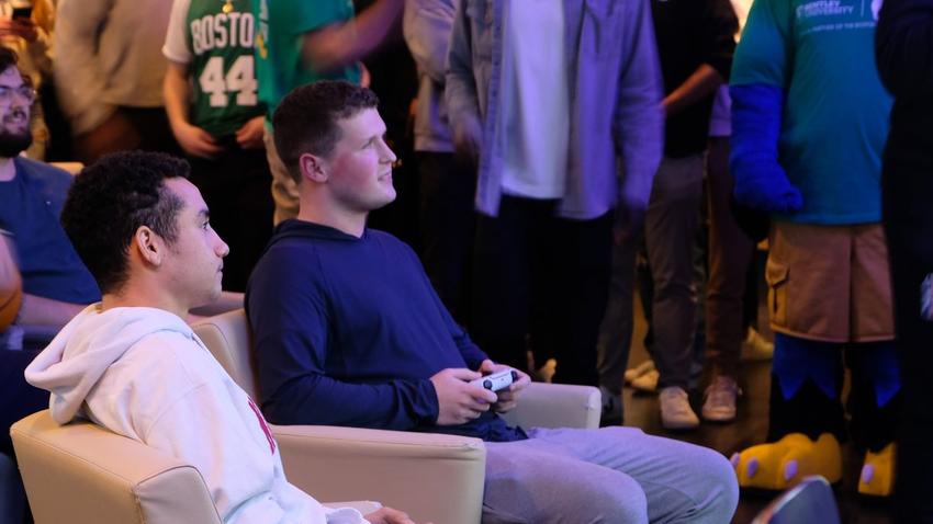 Bentley student Andrew Lussier ’26 competes in the CLTX Shamrock Showdown Collegiate NBA 2K Tournament against a Northeastern student in front of a crowd at Harry's Pub at Bentley