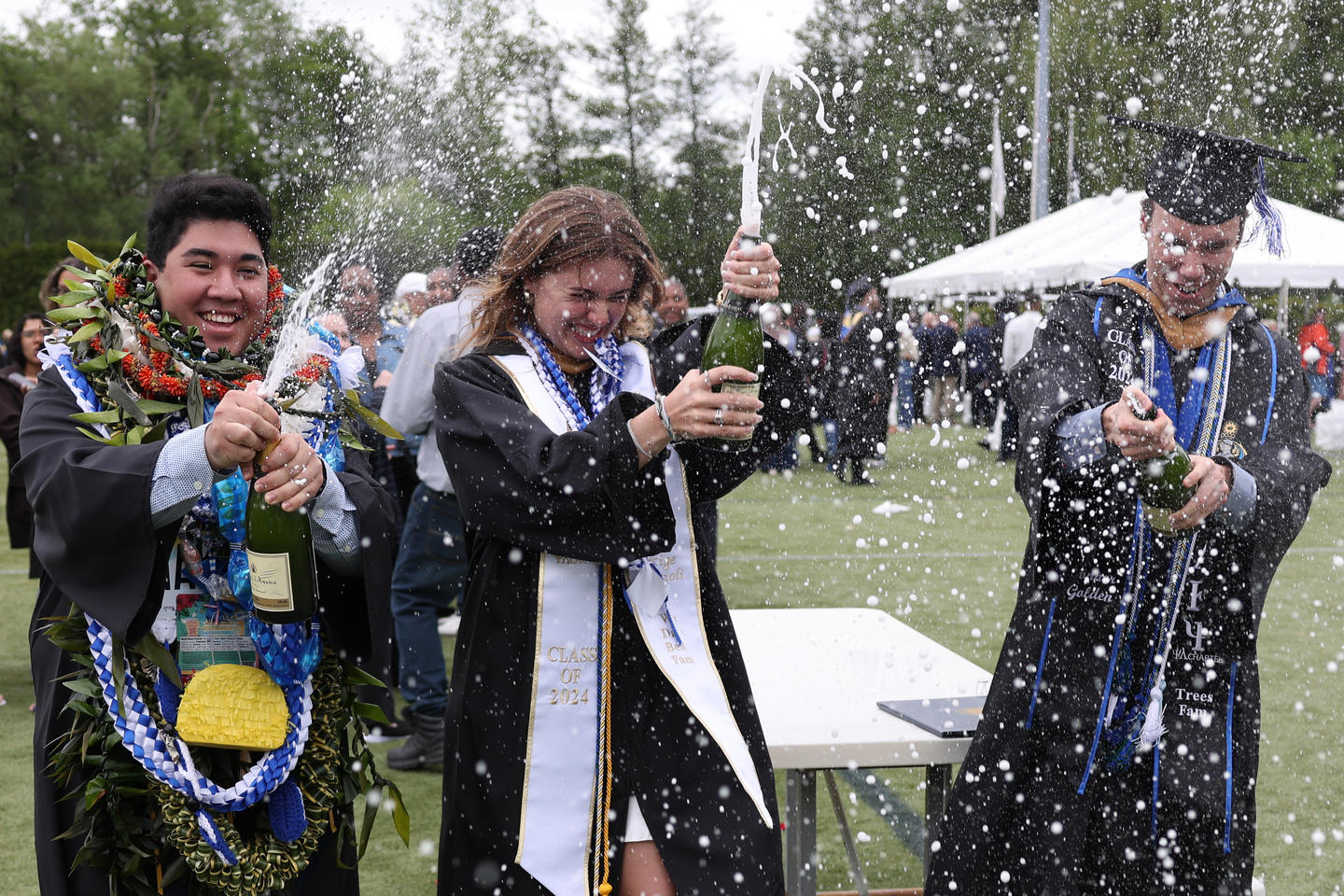 Class of 2024 graduate popping champagne