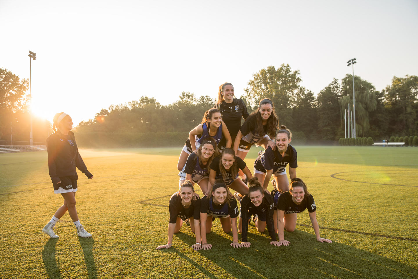 students create pyramid on grass field 