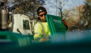 Waste management employee on the Bentley University campus empties a recycle bin